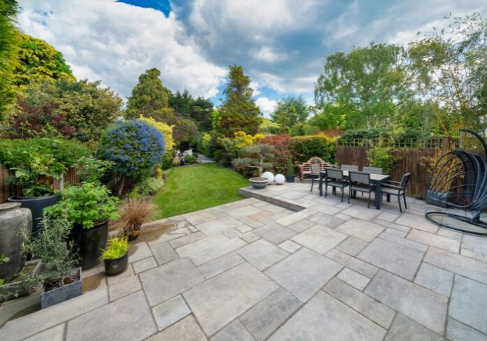 Spacious backyard with a large patio, dining set, and lush landscaping.